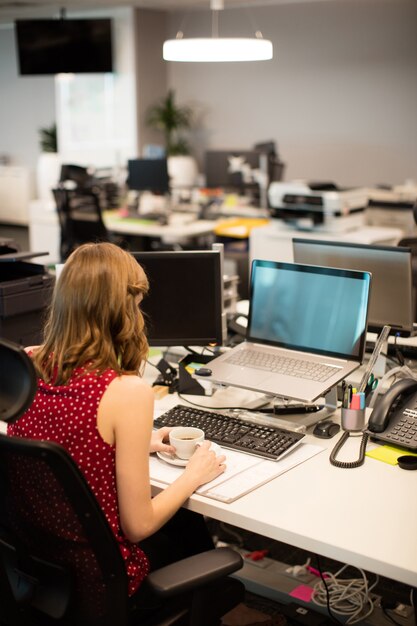 Businesswoman Holding Tasse De Café Tout En Travaillant Au Bureau