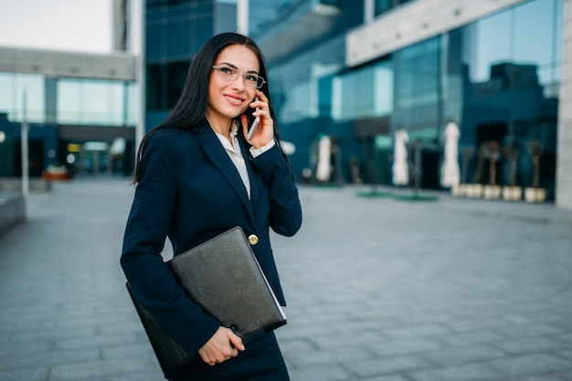 Businesswoman in suit parle par téléphone en plein air