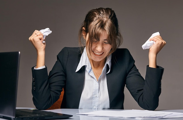 Businesswoman sitting at desk papiers froissés couverts