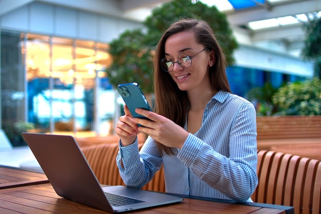 Businesswoman smart casual moderne à l'aide de téléphone et ordinateur portable pour travailler à distance en ligne dans un lieu public