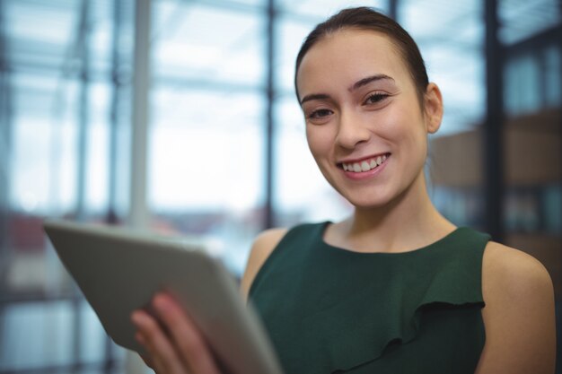 Businesswoman smiling lors de l'utilisation de la tablette numérique