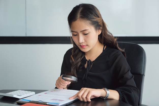 Businesswoman using loupe pour examiner le bilan annuel