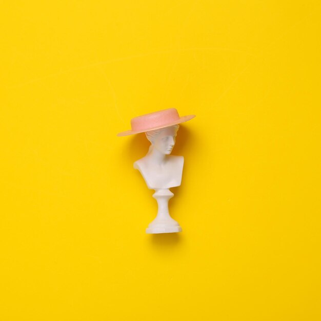 Buste de Vénus avec un chapeau sur fond jaune Mode minimale nature morte Plain couché
