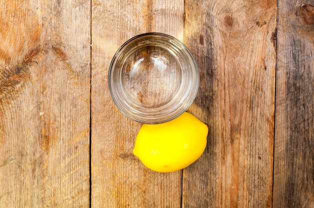 Buvez dans un verre et un citron sur un fond de planches de bois