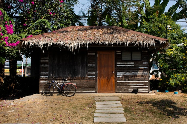 Cabane en bois rétro vintage ou chalet en bois avec vélo classique pour les thaïlandais et les voyageurs étrangers se reposer se détendre dans la ferme du parc-jardin du village de campagne de la ville de Sam Phran à Nakhon Pathom en Thaïlande