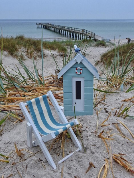 Photo cabane miniature bleue et chaise longue sur une plage de sable
