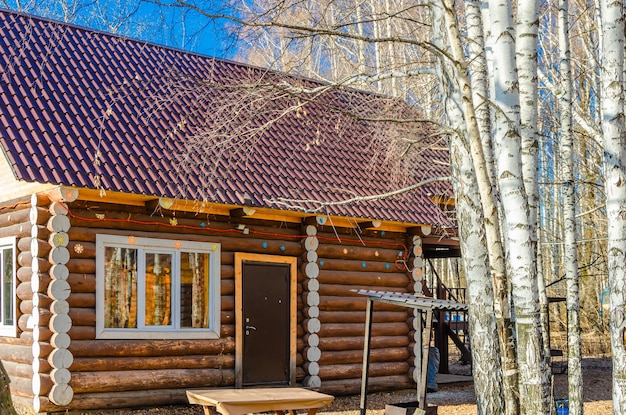 Une cabane en rondins avec une table et des bancs devant des arbres.