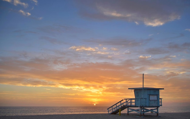 Cabane de sauveteur sur la plage contre un ciel spectaculaire au coucher du soleil