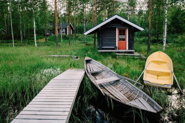 Cabane traditionnelle en bois Sauna finlandais sur le lac et jetée avec bateaux de pêche Paysage d'été