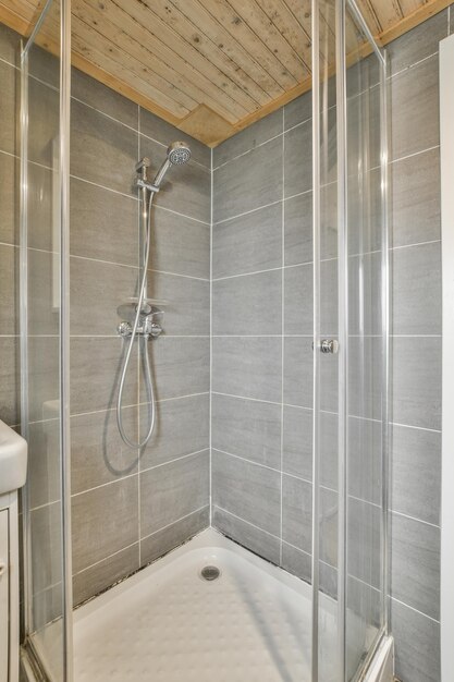 Cabine de douche moderne avec porte vitrée dans une salle de bain lumineuse au carrelage gris