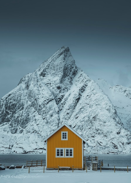 Cabine jaune encadrée par le pic enneigé sur les îles Lofoten, Norvège