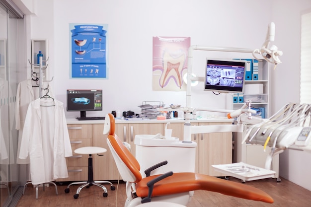 Cabinet de dentiste orange moderne avec ustensiles stériles. Cabinet de stomatologie avec personne dedans et équipement orange pour le traitement oral.
