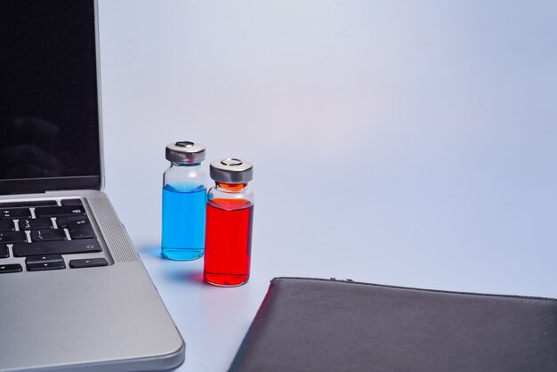 Cabinet de médecin avec lieu de travail moderne dans une clinique médicale. Ordinateur portable, ampoules de médicaments et bloc-notes sur la vue de dessus de table.