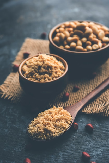 Cacahuètes concassées ou poudre de mungfali avec de l'arachide entière et grillée. Servi dans un bol sur fond de mauvaise humeur. Mise au point sélective