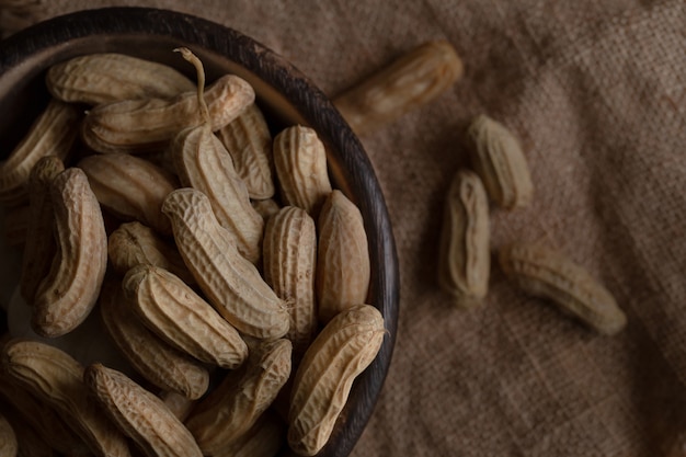 Cacahuètes en noix de coco dans un bol de bois sur un sac