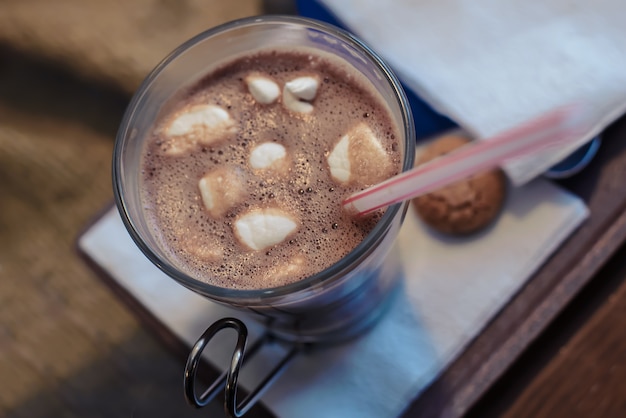 Cacao aux guimauves dans une tasse en verre avec une paille sur la table