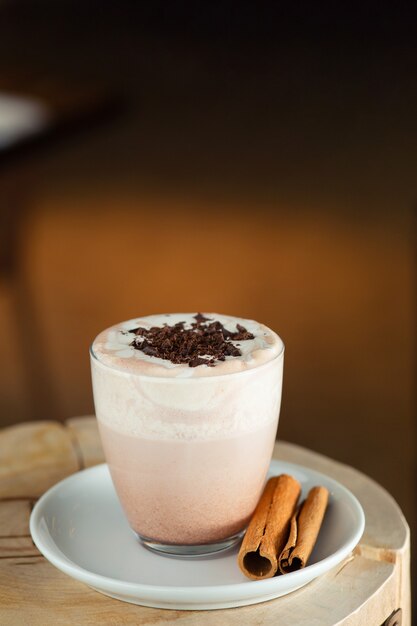 Cacao à la cannelle et au chocolat en gros plan sur des supports en bois et fond sombre.