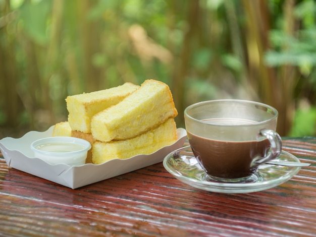 Cacao chaud dans une tasse avec du pain cuit au four avec du beurre et du lait condensé