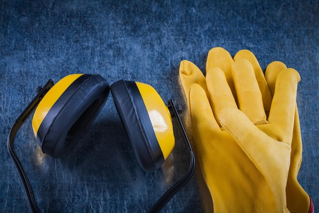 Photo cache-oreilles de protection jaune et gants en cuir sur le concept de construction de surface métallique rayée