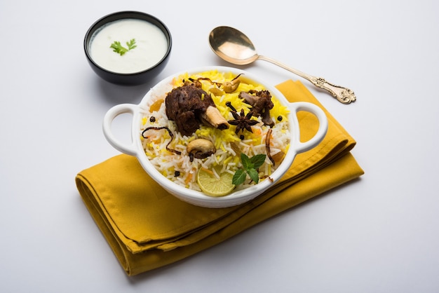 Cachemire Mutton Gosht ou Lamb Biryani préparé dans du riz basmati servi avec trempette au yaourt sur fond de mauvaise humeur, mise au point sélective