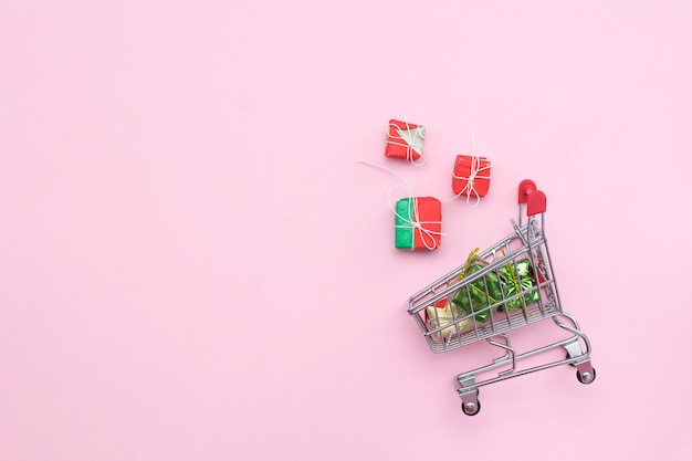 Caddie sur un fond rose avec des cadeaux, vue de dessus. CopySpace. affaires, ventes, achats de Noël.