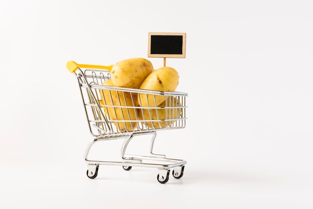 Caddie rempli de pommes de terre sur fond blanc