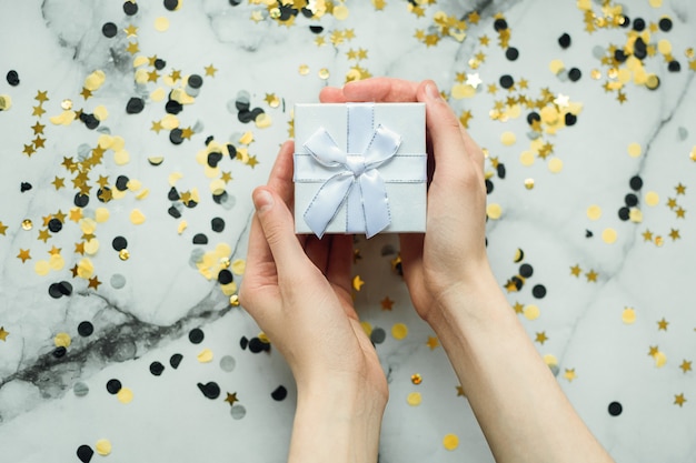 Cadeau en argent dans les mains d'une fille sans manucure