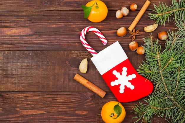Cadeau en chaussette de Noël, mandarine, bonbon, noix, cannelle sur bois foncé