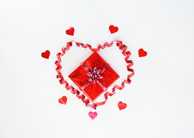 Cadeau dans une boîte rouge avec un ruban en forme de coeur sur fond blanc pour la Saint-Valentin.