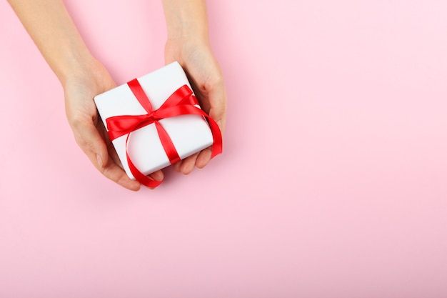 Cadeau dans les mains des femmes sur une vue de dessus de fond coloré