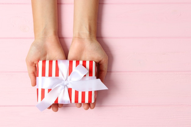 Cadeau dans les mains des femmes sur une vue de dessus de fond coloré