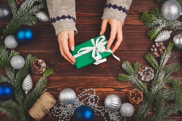 Cadeau décoré avec ruban entouré de décorations de Noël sur une table en bois