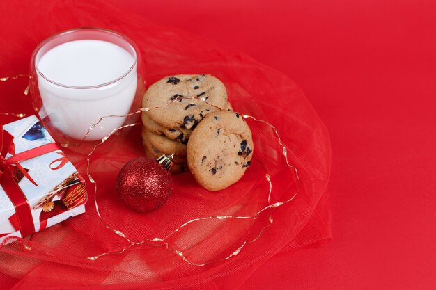 Cadeau Du Nouvel An, Biscuits Aux Pépites De Chocolat Et Un Verre De Lait Sur Fond De Noël Rouge