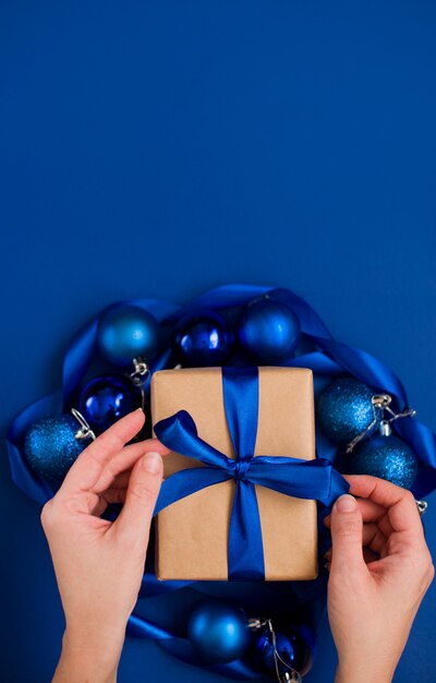 Cadeau du Nouvel An sur une surface bleue, avec un beau ruban de satin. Noël. Contenu du Nouvel An.