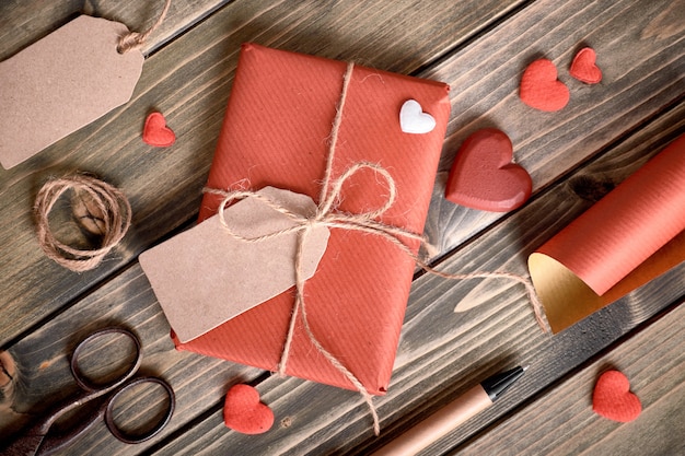 Cadeau emballé attaché avec un cordon, une étiquette en carton avec le texte "Happy Valentine" et des matériaux d'emballage