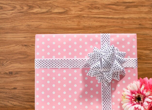 Cadeau enveloppé dans du papier rose avec des pointes blanches et un beau nœud cadeau sur la table Humeur festive et surprise