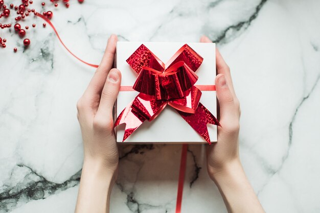 Cadeau fait à la main entre les mains d'une fille avec une manucure Nude