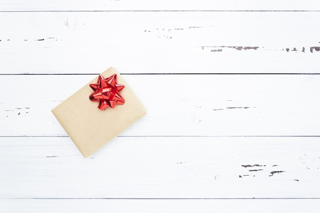 Cadeau sur un fond en bois blanc avec un arc rouge