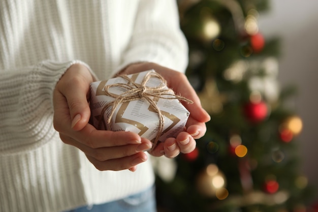 Cadeau en mains pour noël ou nouvel an sur fond d'intérieur décoré