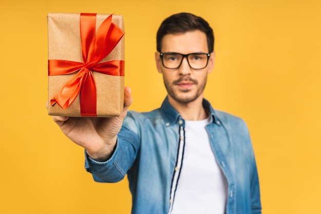 Cadeau merveilleux Adorable photo d'un homme barbu attrayant avec un beau sourire tenant une boîte de cadeau d'anniversaire isolée sur fond jaune