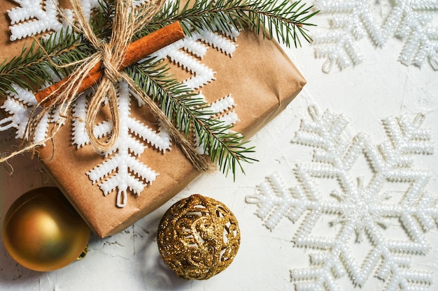 Cadeau de Noël ou boîte cadeau emballée dans du papier kraft avec décoration sur fond blanc rustique