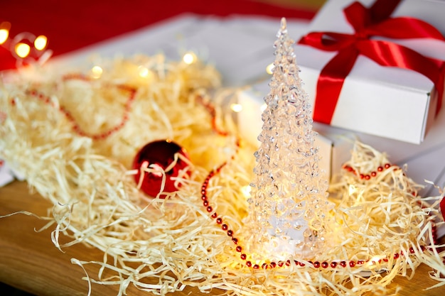 Cadeau de Noël bricolage enveloppant une boîte blanche de cadeau de Noël avec un ruban rouge, décoration festive sur la table.