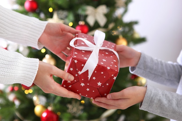 Cadeau de Noël ou du nouvel an dans les mains contre un intérieur décoré