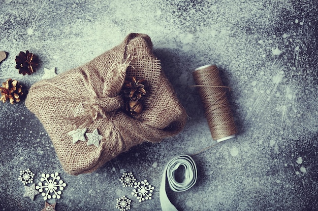 Cadeau de Noël emballé dans de la toile de jute. Corde en lin et décorations en bois