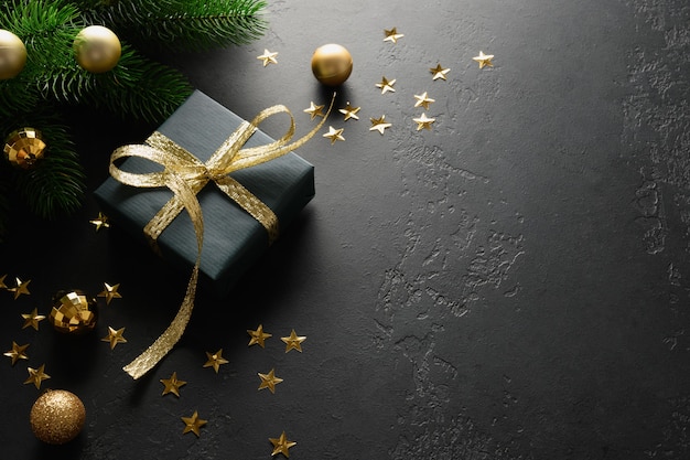 Cadeau de Noël noir avec ruban doré décoratif sur surface noire.
