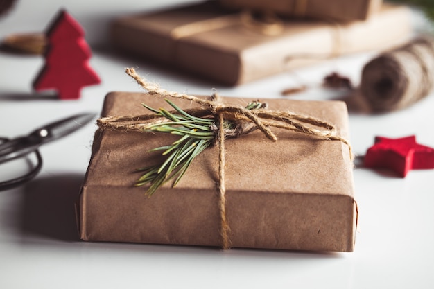 Cadeau en papier kraft dans une couronne de sapins de Noël. Ambiance de Noël, nouvel an, sur fond blanc