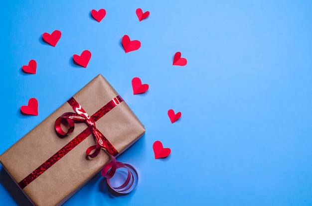 cadeau en paquet avec ruban rouge et coeurs en reconnaissance de l'amour sur fond bleu pour le nouvel an, Noël, Saint Valentin, anniversaire.