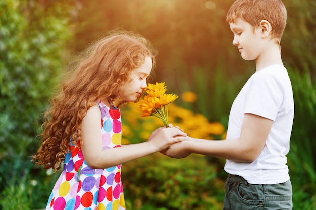 Le cadeau de petit garçon fleurit son amie.