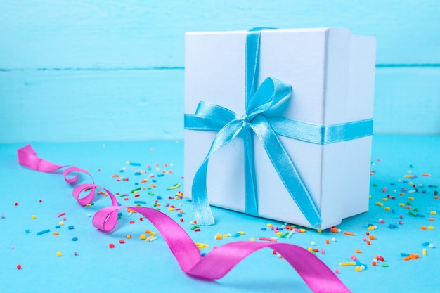 Cadeau, petite boîte attachée avec un ruban de satin bleu. Concept de cadeau. Surprises et cadeaux pour vos proches, félicitations pour les vacances, offrez des cadeaux