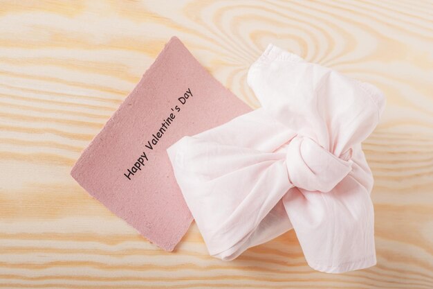 Cadeau romantique enveloppé dans un tissu réutilisable rose sur une vue de dessus de fond en bois